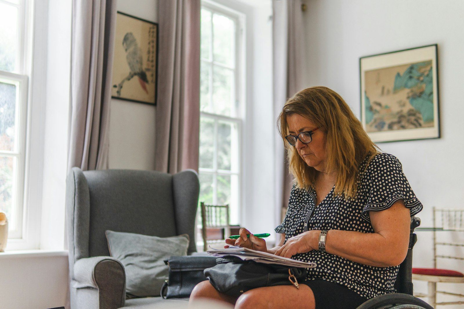 A woman reviewing NHS funding paperwork at home in her living room.