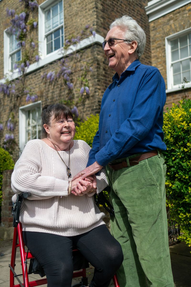 A couple holding hands outside their home.